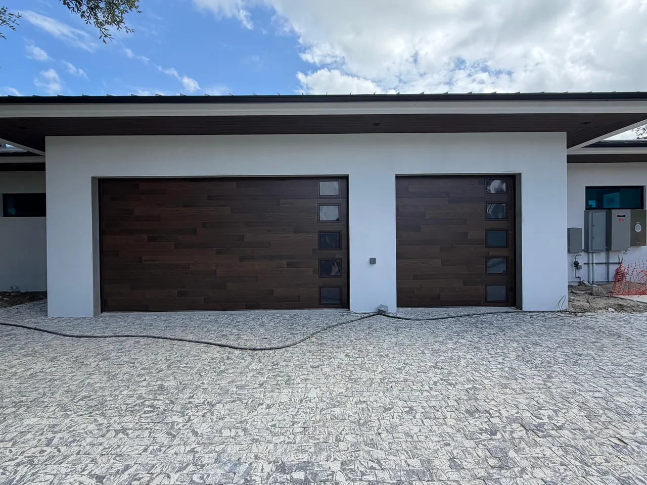 Wood-look garage doors with window lites installed by Outstanding on a modern home in South Florida